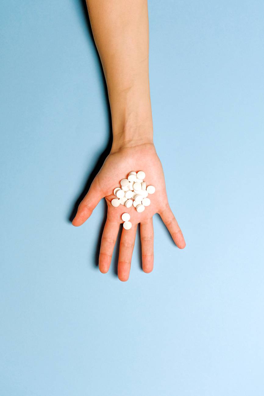 person holding white round medication pills
